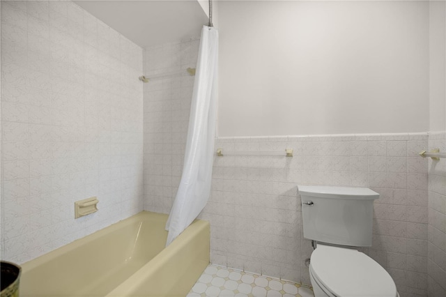 bathroom featuring toilet, a wainscoted wall, tile walls, and shower / tub combo with curtain