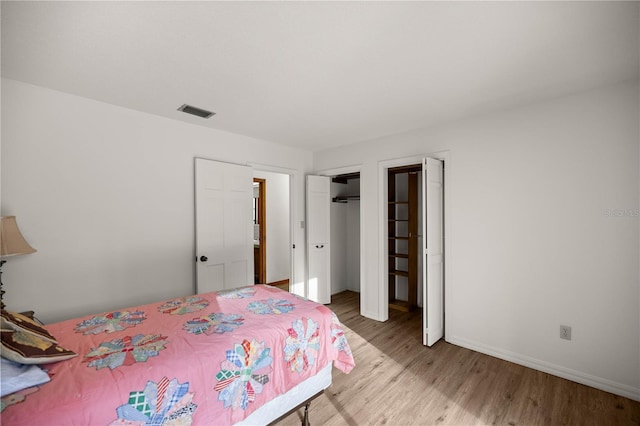 unfurnished bedroom with wood finished floors, visible vents, and baseboards