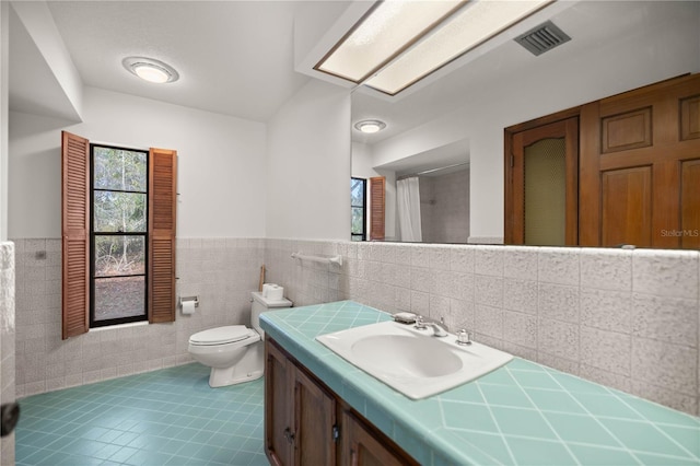 bathroom featuring visible vents, wainscoting, toilet, tile patterned flooring, and vanity