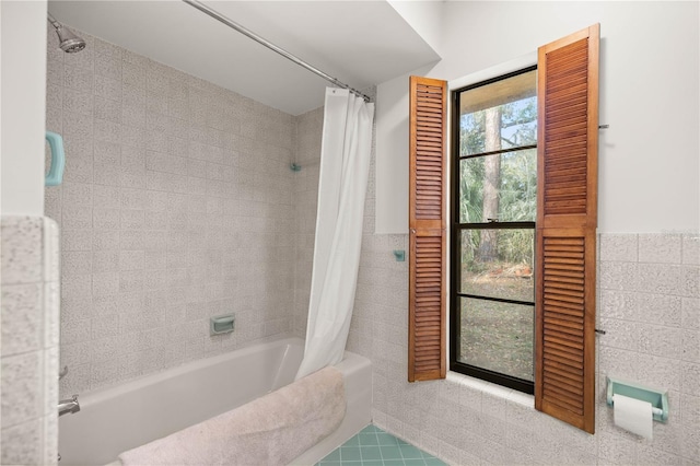 bathroom featuring a wainscoted wall, shower / tub combo with curtain, and tile walls