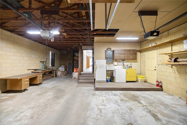 garage with washing machine and dryer, freestanding refrigerator, a sink, and a garage door opener