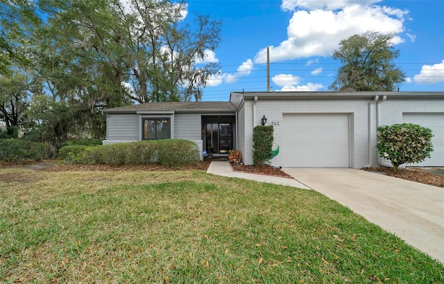 view of front facade with a garage, brick siding, driveway, and a front lawn