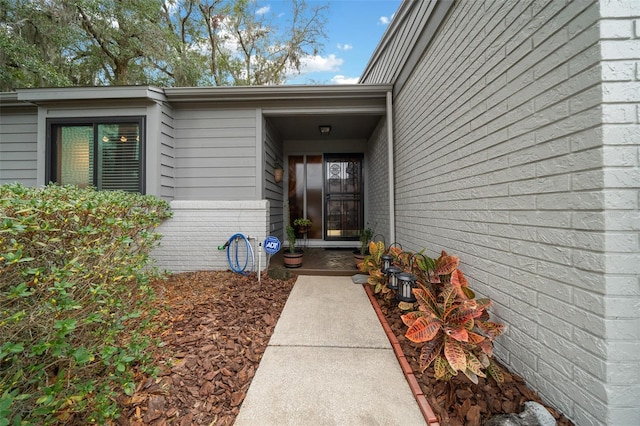 view of exterior entry featuring brick siding