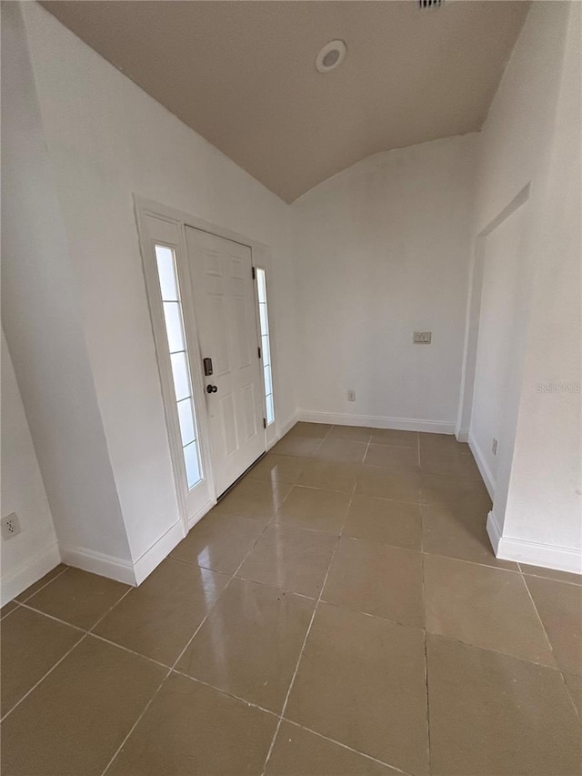 entrance foyer with tile patterned floors, baseboards, and lofted ceiling