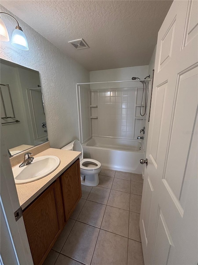 bathroom featuring vanity, visible vents, a textured ceiling, tile patterned floors, and a textured wall