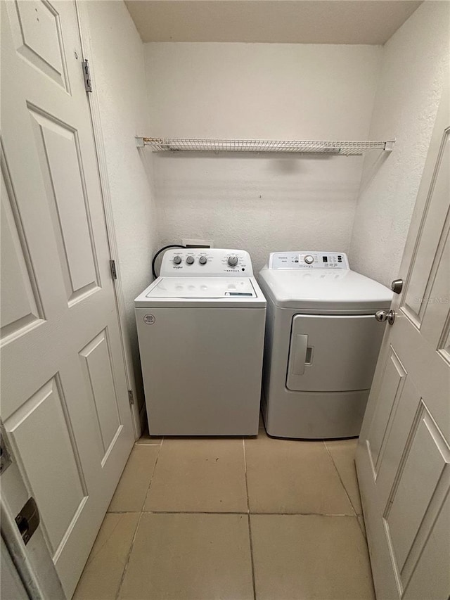 laundry room with laundry area, light tile patterned floors, and washing machine and dryer