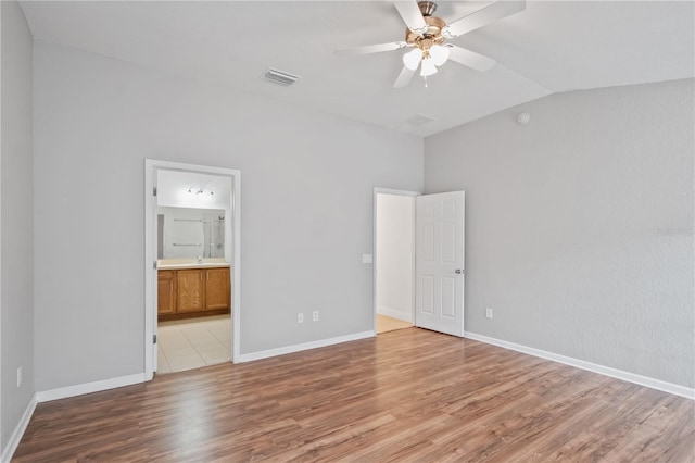 4954 SW 40th Pl, Ocala, FL 34474 - unfurnished bedroom featuring lofted ceiling, light wood-type flooring, baseboards, ensuite bathroom, and a sink