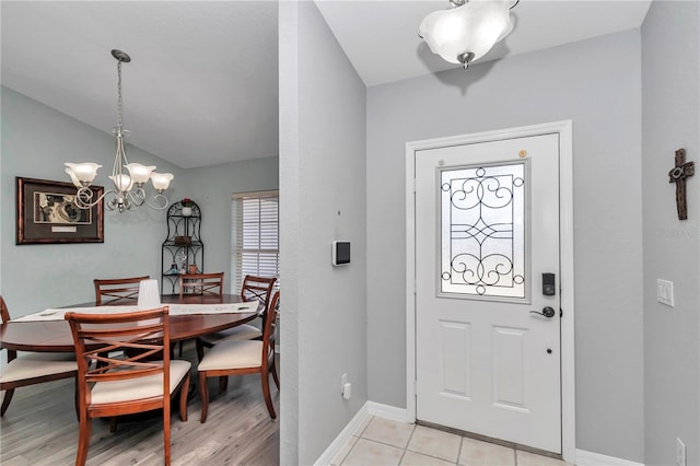 entryway with a healthy amount of sunlight, an inviting chandelier, baseboards, and lofted ceiling