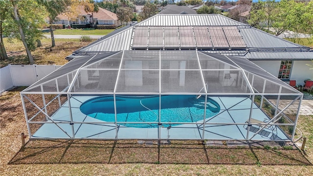 outdoor pool featuring glass enclosure, fence, and a patio