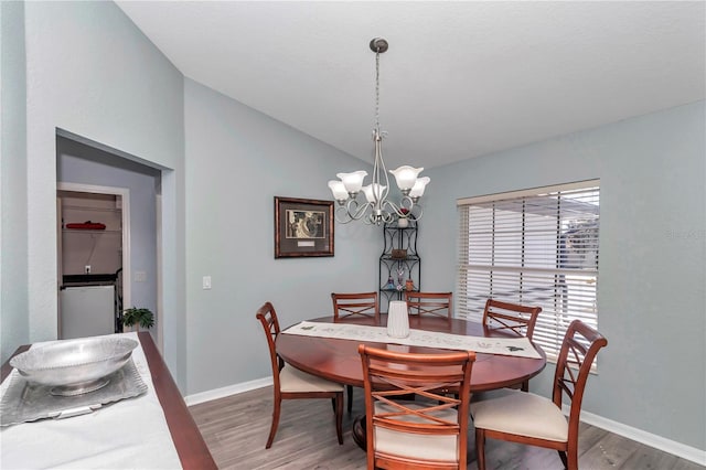 dining area featuring vaulted ceiling, baseboards, wood finished floors, and an inviting chandelier