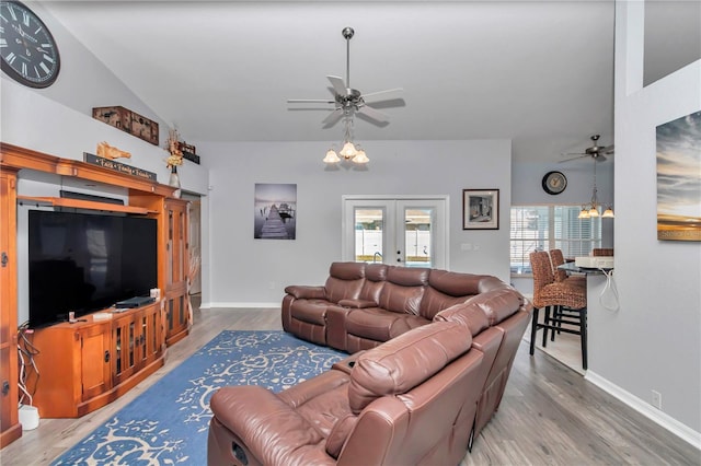 living area with baseboards, lofted ceiling, wood finished floors, french doors, and ceiling fan with notable chandelier