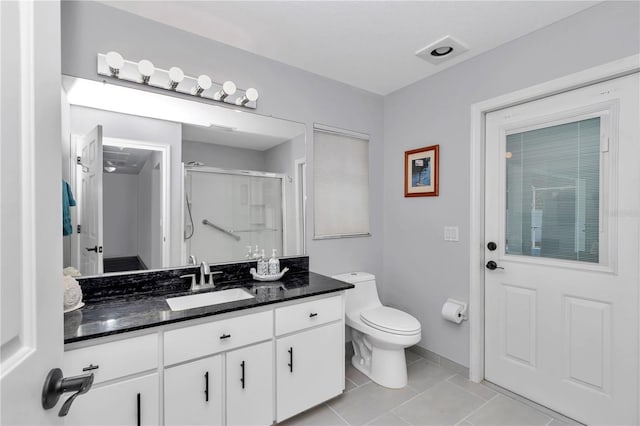 bathroom with toilet, a stall shower, tile patterned flooring, and vanity