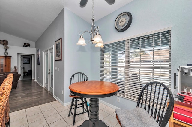 dining space with a notable chandelier, vaulted ceiling, baseboards, and light tile patterned floors