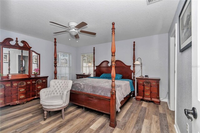 bedroom with a ceiling fan, a textured ceiling, and wood finished floors