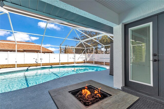 view of pool with glass enclosure, an outdoor fire pit, a patio, a fenced backyard, and a fenced in pool