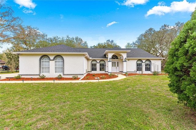 ranch-style house with a shingled roof, a front yard, and stucco siding