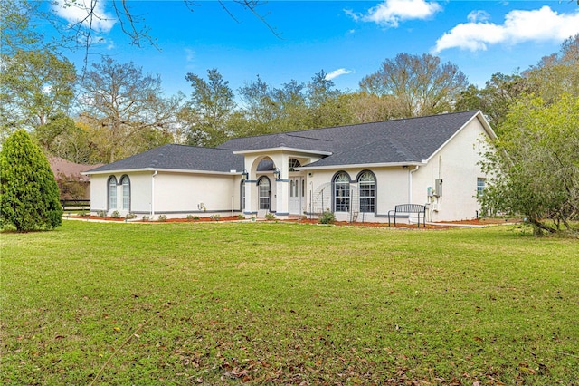 view of front facade with a shingled roof, a front yard, and stucco siding