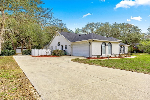 view of front of house with a garage, driveway, fence, a front lawn, and stucco siding