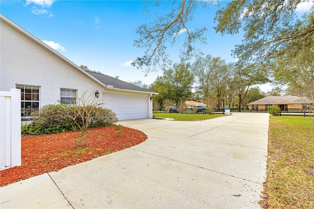 view of property exterior with driveway, a yard, an attached garage, and stucco siding