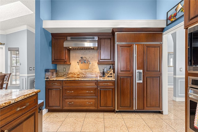 kitchen featuring ornamental molding, built in appliances, light stone countertops, ventilation hood, and light tile patterned flooring