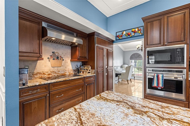 kitchen with light stone countertops, crown molding, black appliances, backsplash, and exhaust hood