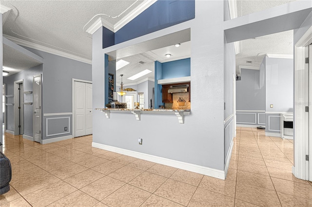 living area featuring ornamental molding, a decorative wall, a textured ceiling, and light tile patterned flooring