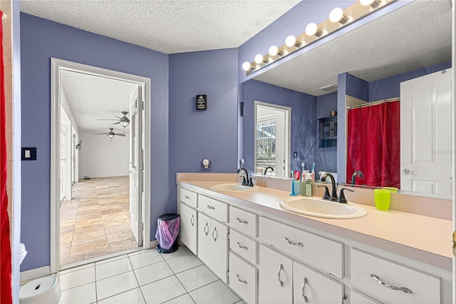 bathroom featuring a textured ceiling, double vanity, a sink, and a ceiling fan