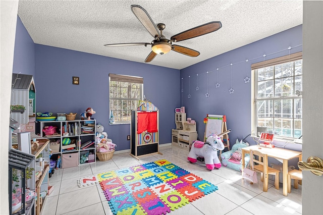 playroom featuring ceiling fan, a textured ceiling, plenty of natural light, and tile patterned floors