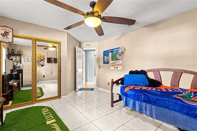 bedroom with light tile patterned floors, a textured ceiling, a ceiling fan, and baseboards