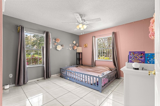 bedroom featuring a ceiling fan, light tile patterned flooring, a textured ceiling, and baseboards