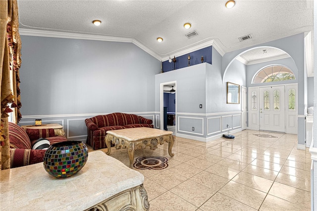 foyer with ornamental molding, lofted ceiling, wainscoting, and visible vents