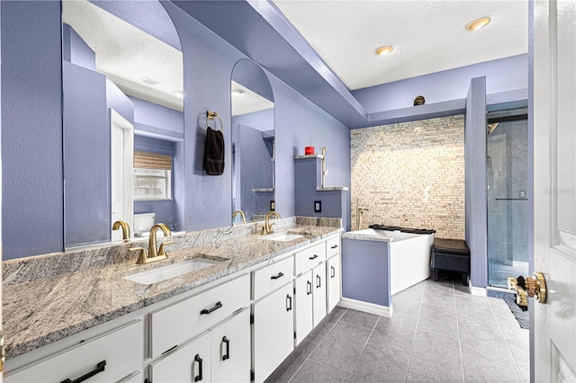 bathroom featuring a textured ceiling, a stall shower, and a sink