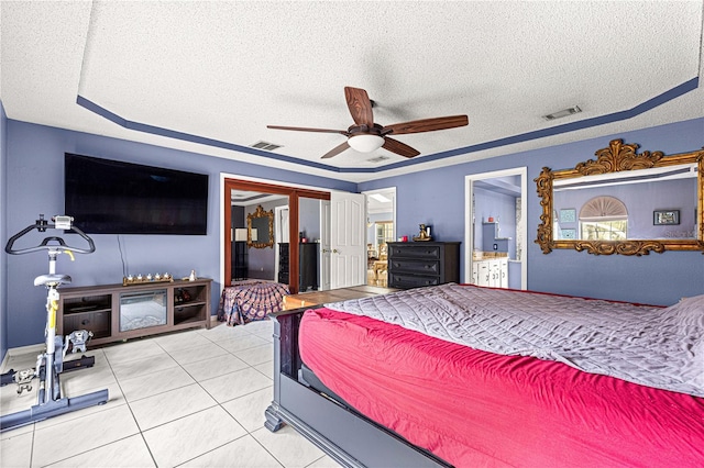 bedroom with light tile patterned floors, a textured ceiling, connected bathroom, and visible vents