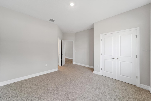 unfurnished bedroom featuring a closet, carpet flooring, visible vents, and baseboards