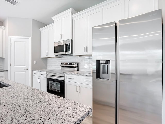 kitchen featuring visible vents, backsplash, appliances with stainless steel finishes, and white cabinetry