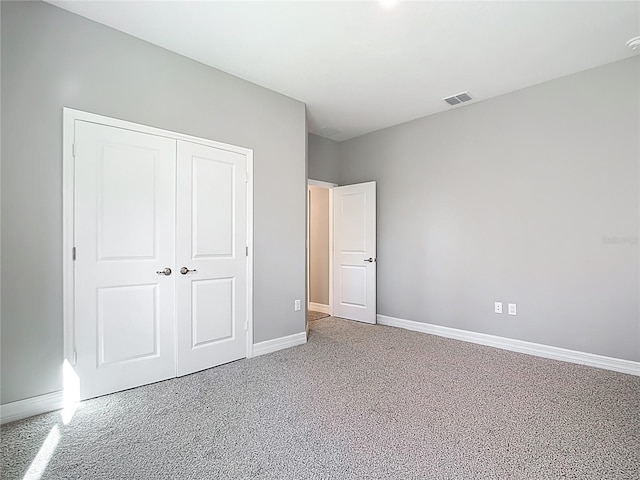 unfurnished bedroom featuring baseboards, visible vents, carpet floors, and a closet