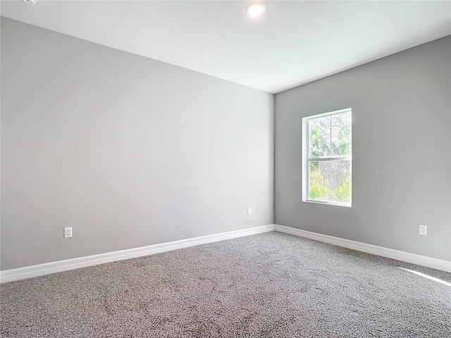 carpeted spare room featuring baseboards