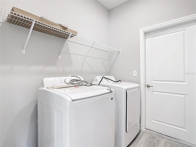 laundry room featuring laundry area, light wood finished floors, and washing machine and clothes dryer