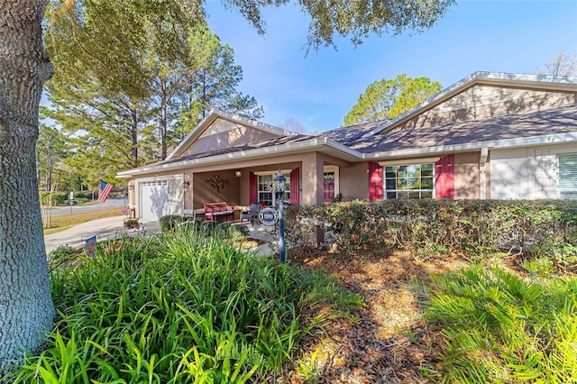 view of front facade with a garage, driveway, and stucco siding