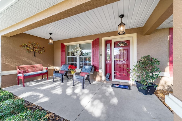 entrance to property featuring covered porch and stucco siding