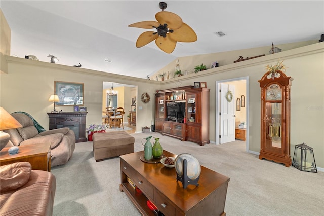 living area featuring light colored carpet, ceiling fan with notable chandelier, visible vents, baseboards, and vaulted ceiling