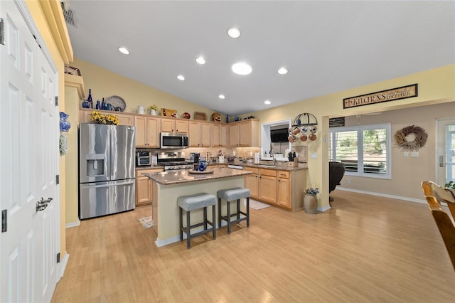 kitchen featuring appliances with stainless steel finishes, light brown cabinets, a sink, and a kitchen island