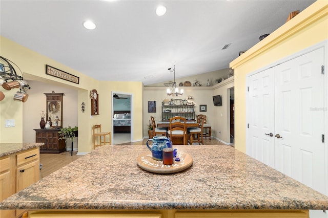 kitchen featuring lofted ceiling, a kitchen island, light stone counters, and recessed lighting