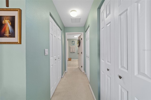 corridor featuring light carpet and baseboards