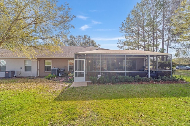 back of house featuring a sunroom, a lawn, central air condition unit, and stucco siding