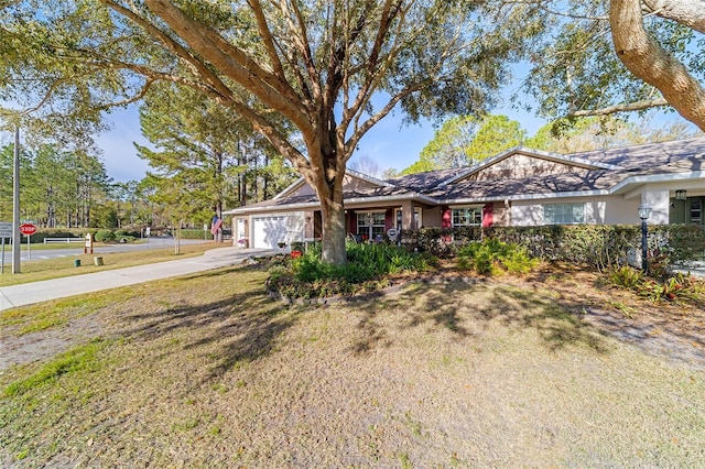 ranch-style house featuring a front yard, concrete driveway, and an attached garage