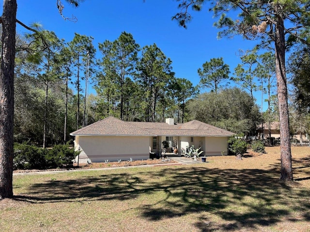 view of front of property with stucco siding, a chimney, and a front yard