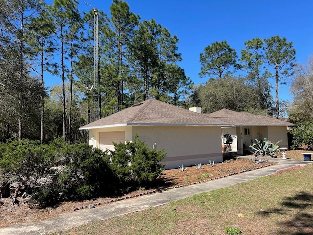 view of property exterior with a garage, roof with shingles, a chimney, and stucco siding