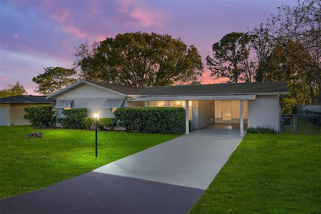 single story home featuring a front yard, concrete driveway, fence, and an attached carport