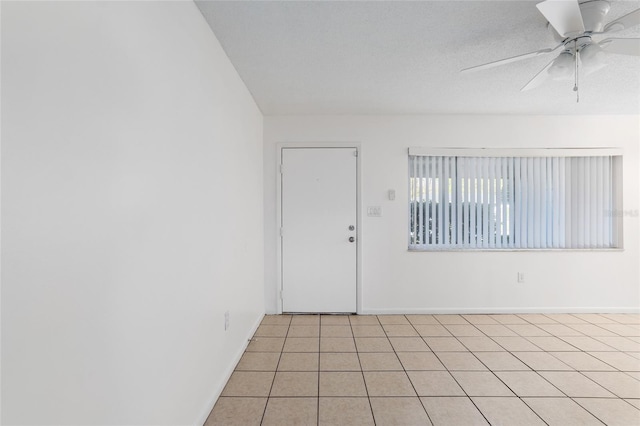 spare room with ceiling fan, baseboards, and light tile patterned flooring